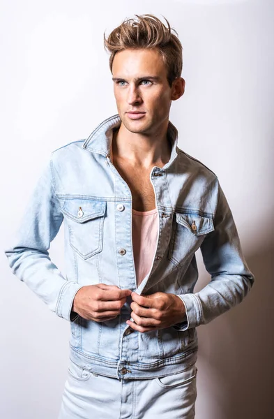 Beau jeune homme en jeans pose de veste en studio . — Photo