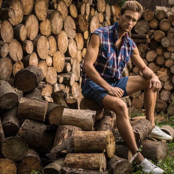 Jonge knappe man in casual shirt poses in de buurt van houten achtergrond. — Stockfoto