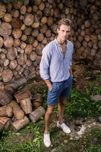 Jovem homem bonito na camisa casual posa perto de fundo de madeira . — Fotografia de Stock