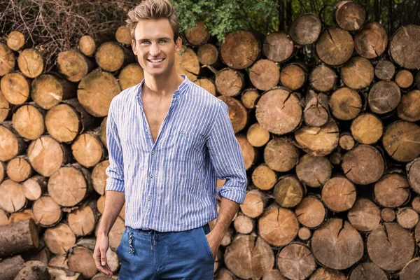 Jonge knappe man in casual shirt poses in de buurt van houten achtergrond. — Stockfoto