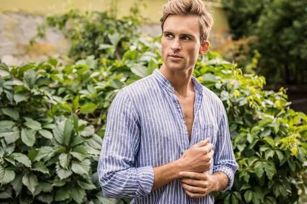 Jonge knappe man in Casual kleren poseren in de zomertuin. — Stockfoto