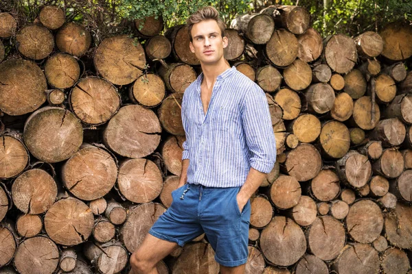 Jovem homem bonito na camisa casual posa perto de fundo de madeira . — Fotografia de Stock