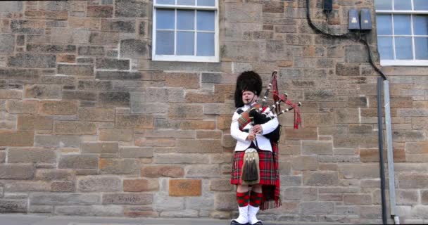 Schotland, Verenigd Koninkrijk - 30 mei 2019: Schotse piper in traditioneel kostuum speelt op Edinburgh street. 4k Beelden. — Stockvideo