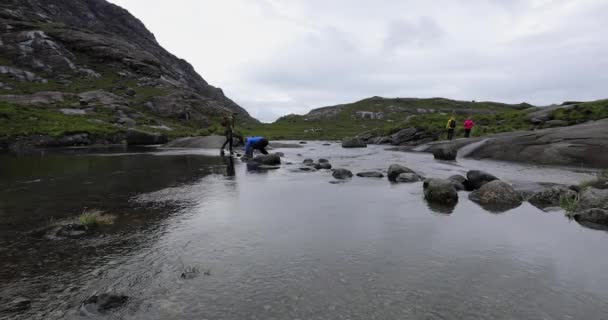 Szkocja, Zjednoczone Królestwo - 30 maja 2019: Grupa podróżnych krzyżuje kamienie w rzece. — Wideo stockowe