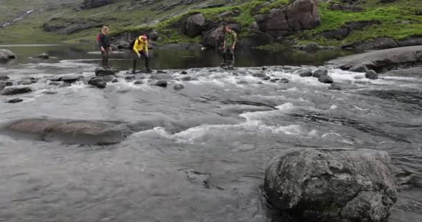 Schotland, Verenigd Koninkrijk - 30 mei 2019: Groep reizigers steekt stenen over in de rivier. — Stockvideo