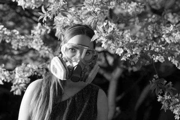 Young beautiful girl portrait in a mask with degree of protection 3M posing in twilight of spring garden.