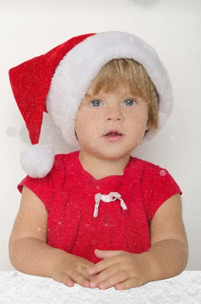 Bebê vestido como Papai Noel sob a neve caindo — Fotografia de Stock