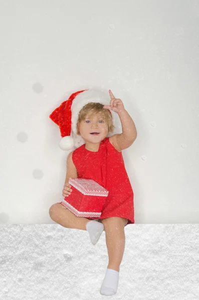 Petite fille en costume de Père Noël, flocons de neige avec cadeau — Photo