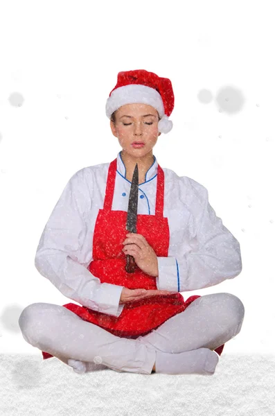 Cook in Santa hat, yoga, knife under snow — Stock Photo, Image