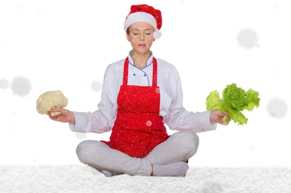 Cook in Santa hat, yoga, vegetables under snow — Stock Photo, Image