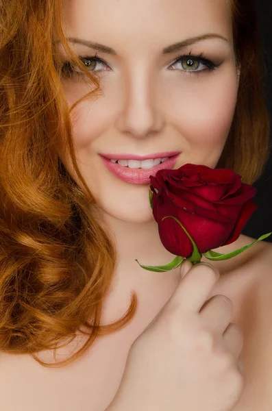 Young woman with red hair holds rose in her hands — Stock Photo, Image