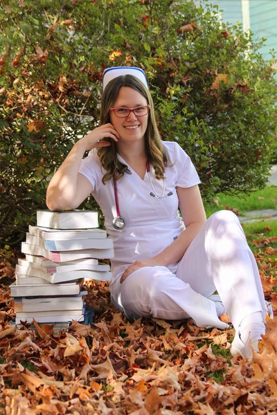 Enfermera joven con gorra y libros al aire libre Imagen de archivo