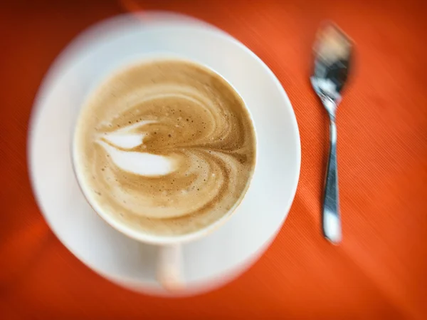 Cappuccino café quente latte em uma xícara na mesa de madeira com colher — Fotografia de Stock