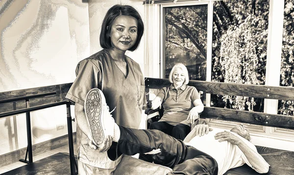 Старший пенсионер при содействии медсестры в реабилитационной клинике — стоковое фото