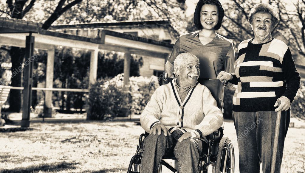 Elder people in rehab facility garden with nurse