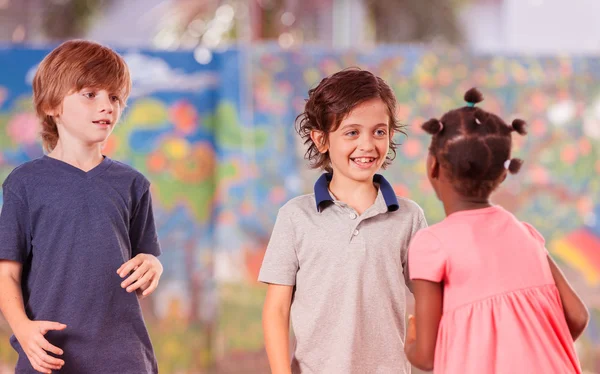 Blandad ras klasskamrater spelar på skolgård — Stockfoto