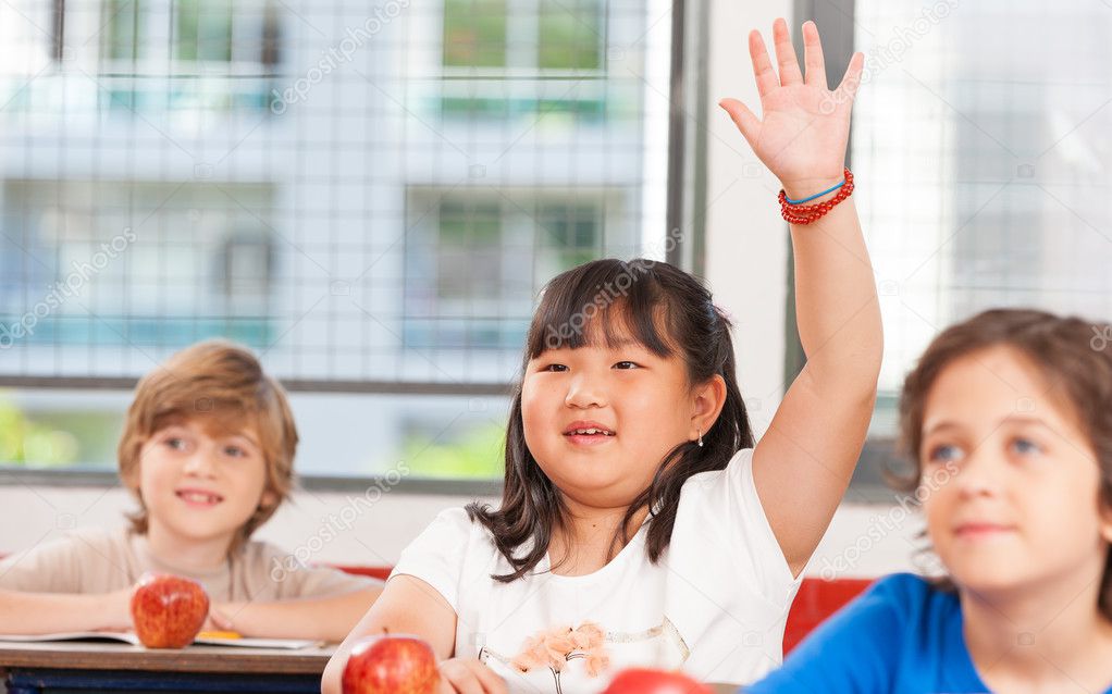 Schoolchild raising hand in classroom. Education concept