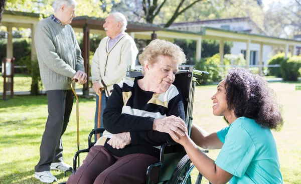 Infirmière afro-américaine réconfortante vieille femme en fauteuil roulant, hôpital — Photo