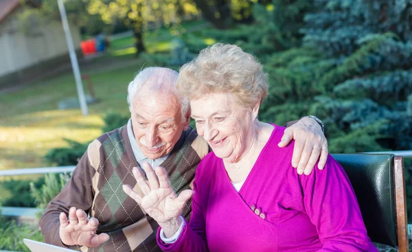 Ouderling paar buiten genieten van computerscherm — Stockfoto