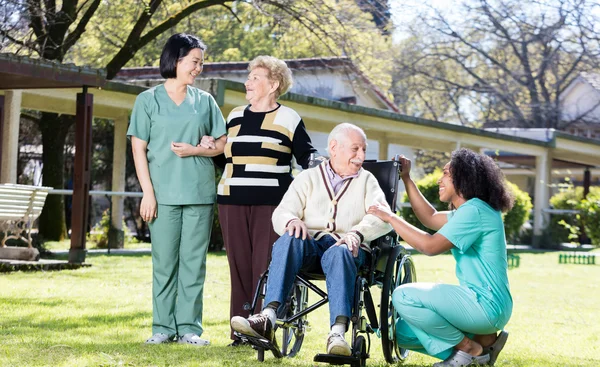 Afroamerican and asian nurses joking with elder people in hospit — Stock Photo, Image