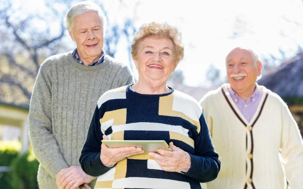 Oudere mensen ontspannen in de tuin met tablet — Stockfoto