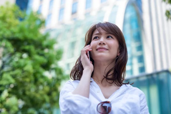 Asian woman speaking at phone in street — Stock Photo, Image