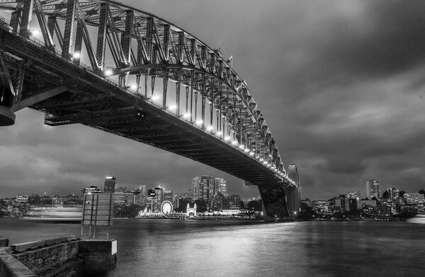 Black and white wide angle view of Sydney Harbour Bridge at nigh