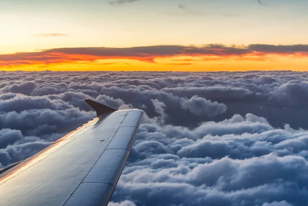 Airplane wing at sunset over sky clouds — Stock Photo, Image