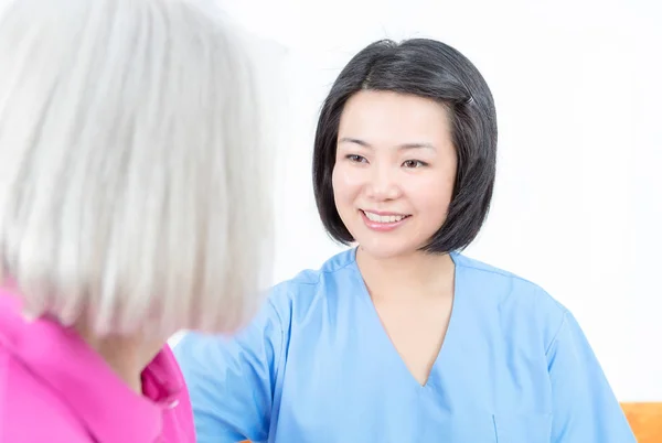 Asian nurse smiling to elder female patient — Stock Photo, Image