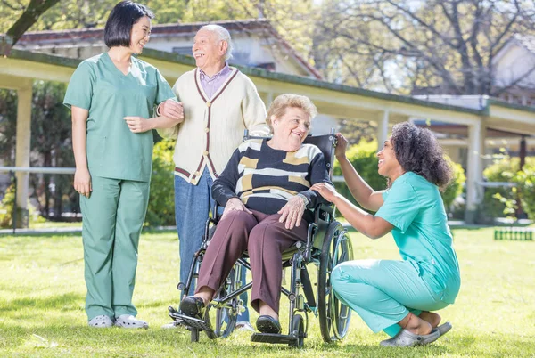 Gelukkig verpleegkundigen en patiënten in rehab kliniek tuin — Stockfoto