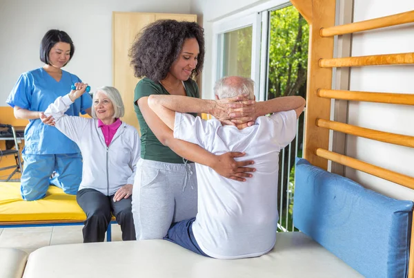 Enfermeira Africano ajudando o homem mais velho com exercícios físicos em — Fotografia de Stock