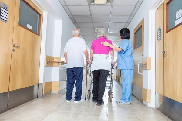 Les patients âgés étant assistés par une infirmière asiatique féminine dans l'utilisation wa — Photo