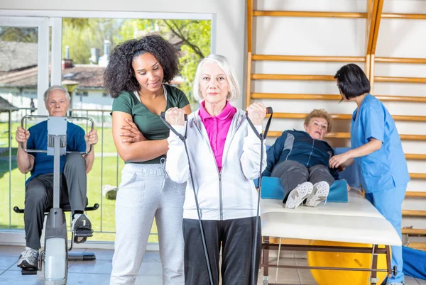 Rehab clinic gym. Multi racial nurses helping elder patients