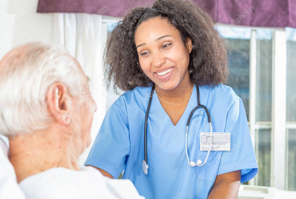 African nurse smiling to elder male patient