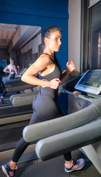Junge Frau in Sportkleidung läuft im Fitnessstudio auf Laufband — Stockfoto