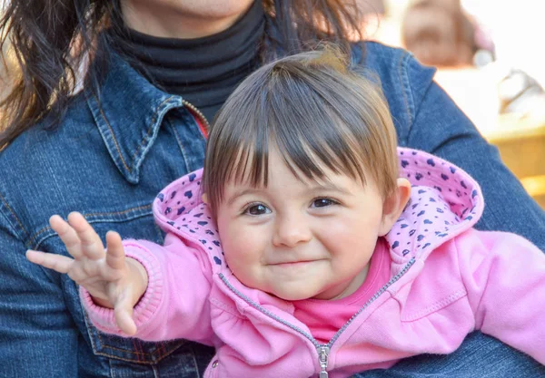 Bebek kız annesinin kollarında ulaşmaya çalışıyor — Stok fotoğraf