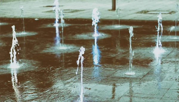 Corrente de água salpicando no chão, fonte da cidade à noite — Fotografia de Stock