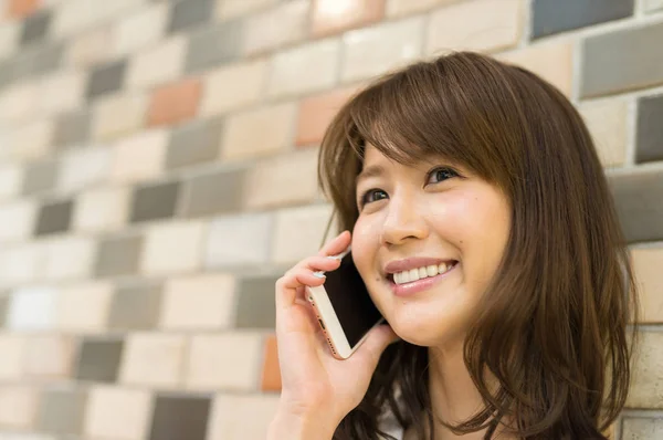 Asian woman outdoor speaking at mobile phone — Stock Photo, Image