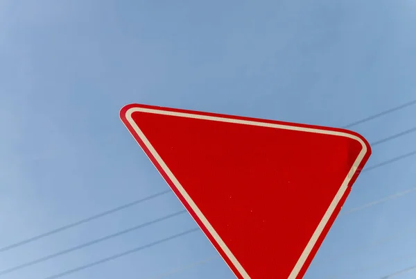 Triangolo rosso strada segno di pericolo contro il cielo blu — Foto Stock