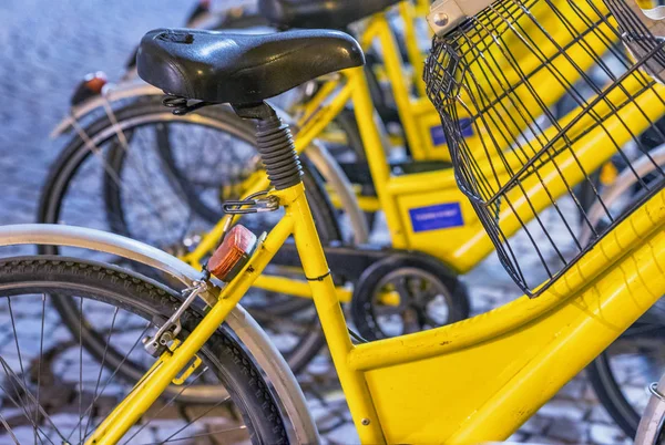 Fila de bicicletas amarillas en el centro de la ciudad por la noche — Foto de Stock