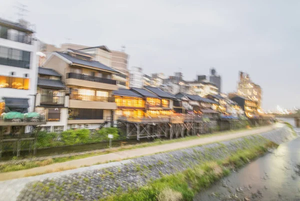 Vue floue sur les bâtiments de Kyoto le long de la rivière après le coucher du soleil — Photo