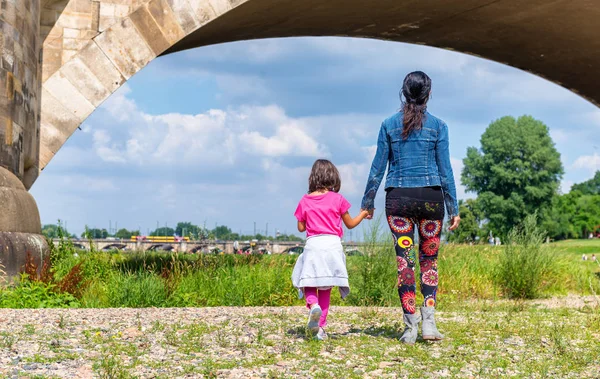 Mãe e filha caminhando sob uma ponte antiga — Fotografia de Stock