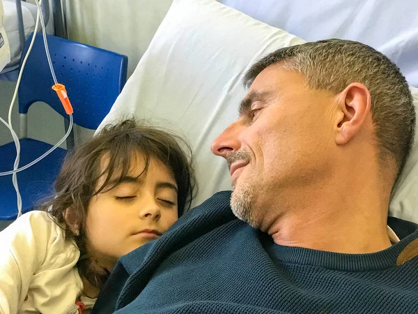 Bambina in letto d'ospedale che dorme sul petto del padre — Foto Stock
