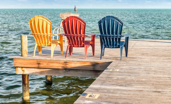 Cadeiras coloridas ao pôr do sol com vista para o mar — Fotografia de Stock