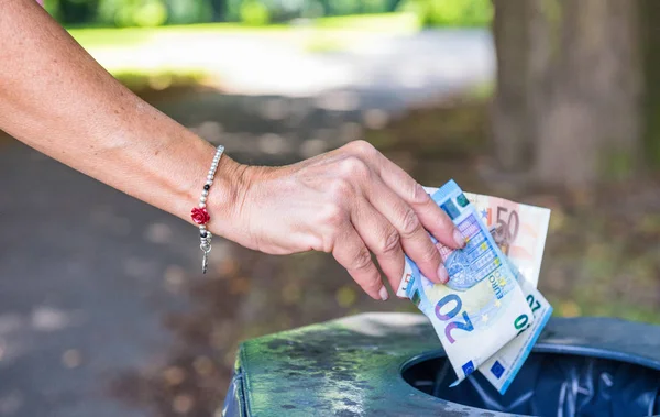 Woman's hand throwing money in public trashcan. Richness and bus — Stock Photo, Image