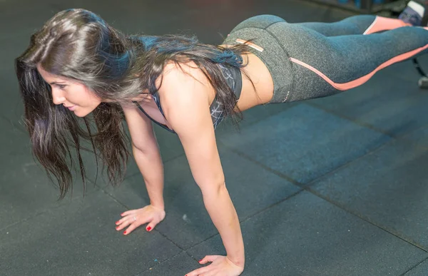 Beautiful girl stretching legs at gym — Stock Photo, Image