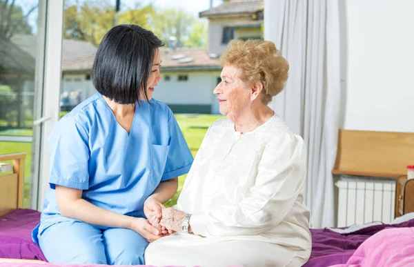 Krankenschwester spricht mit älterer Frau im Krankenhausbett — Stockfoto