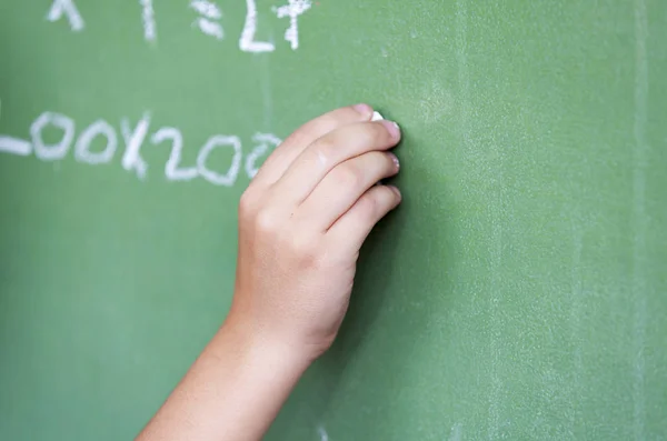 Caucasian child hand writing at chalkboard — Stock Photo, Image