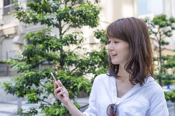 Ázsiai lány szabadtéri látszó-on mozgatható telefon — Stock Fotó