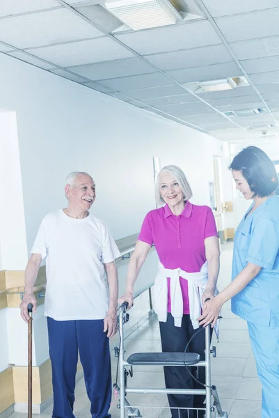 Feliz anciano pareja de seniors en rehabilitación clínica ayudado por asiático —  Fotos de Stock